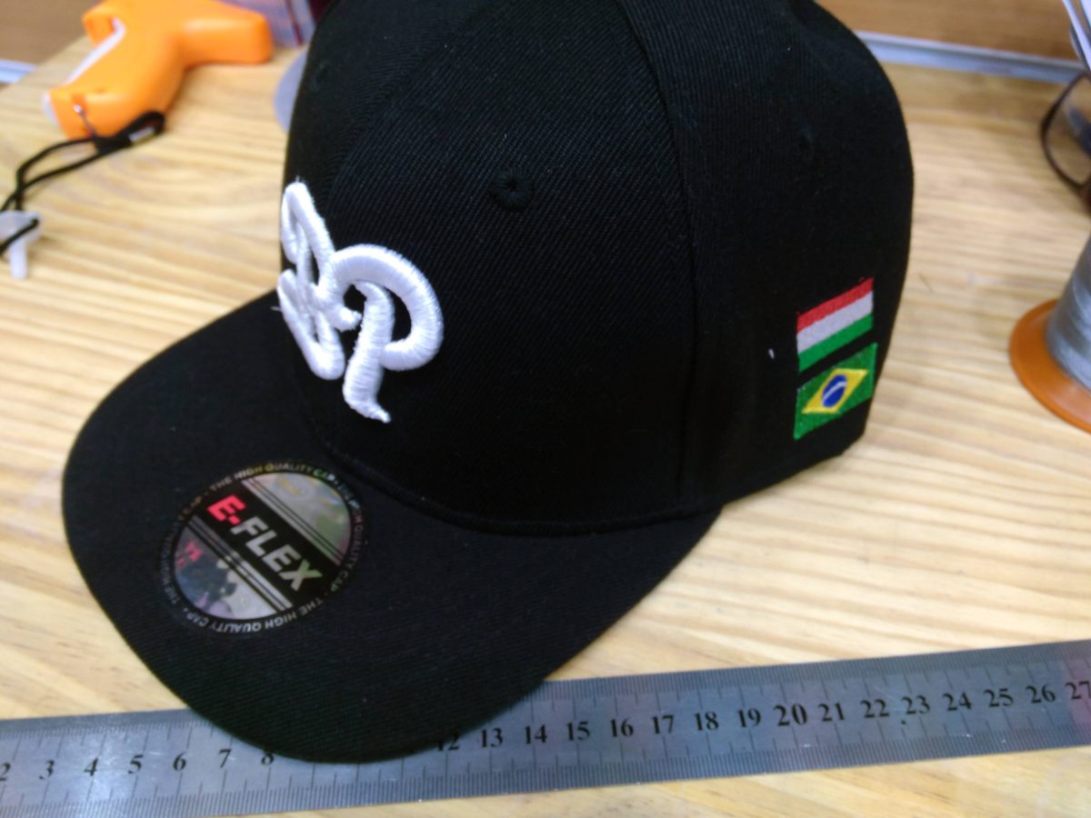 Monograma bordado en 3D puff en una gorra negra junto a una regla