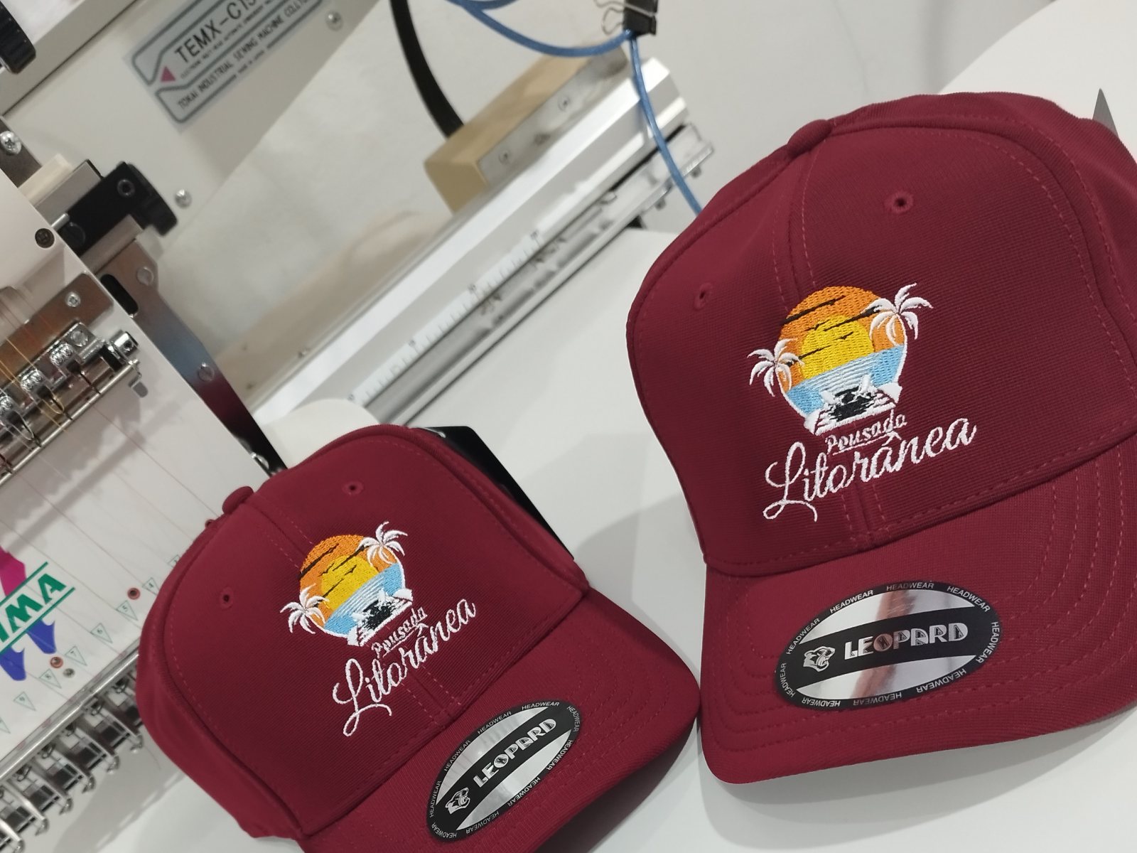 Cap embroidery with script lettering and multicolor fill, three caps on a Tajima