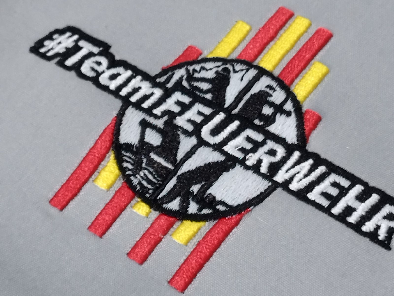 Left chest logo with satin lettering and fine detail fill, sewn on grey polo fabric